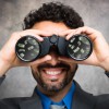 Businessman using binoculars, money reflected in the lens