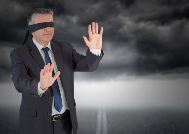 digitally composite image of businessman in blindfold against storm cloud